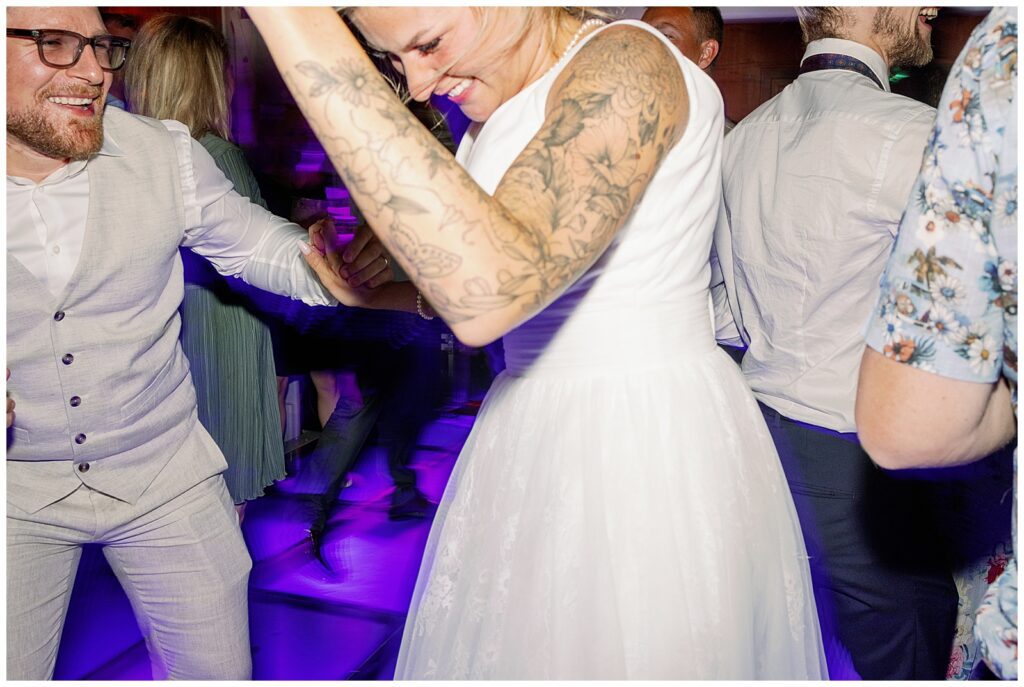Bruden dansar energiskt på dansgolvet under bröllopsfesten på Green Hotel i Tällberg, omgiven av gäster och intensiv stämning. Levande bröllopsfoto i Dalarna av bröllopsfotograf Dalarna. The bride dancing energetically on the dance floor during the wedding party at Green Hotel in Tällberg, surrounded by guests and a lively atmosphere. Dynamic wedding photography in Dalarna by a wedding photographer in Dalarna.