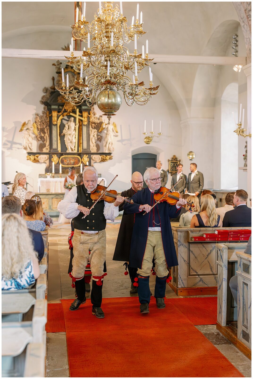 Folkmusiker tågar nerför mittgången i Rättviks kyrka efter musikinslag under vigseln | Folk musicians walking down the aisle in Rättvik Church after performing during the ceremony