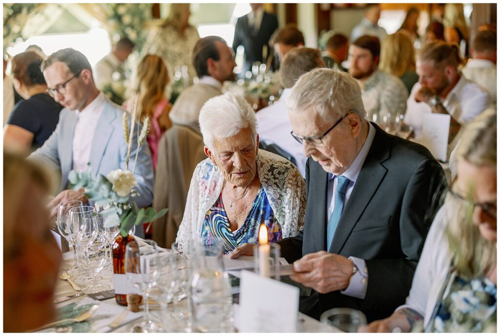 Äldre gäster samtalar och läser program under bröllopsmiddagen på Green Hotel i Tällberg. / Elderly guests chatting and reading the program during the wedding dinner at Green Hotel in Tällberg.