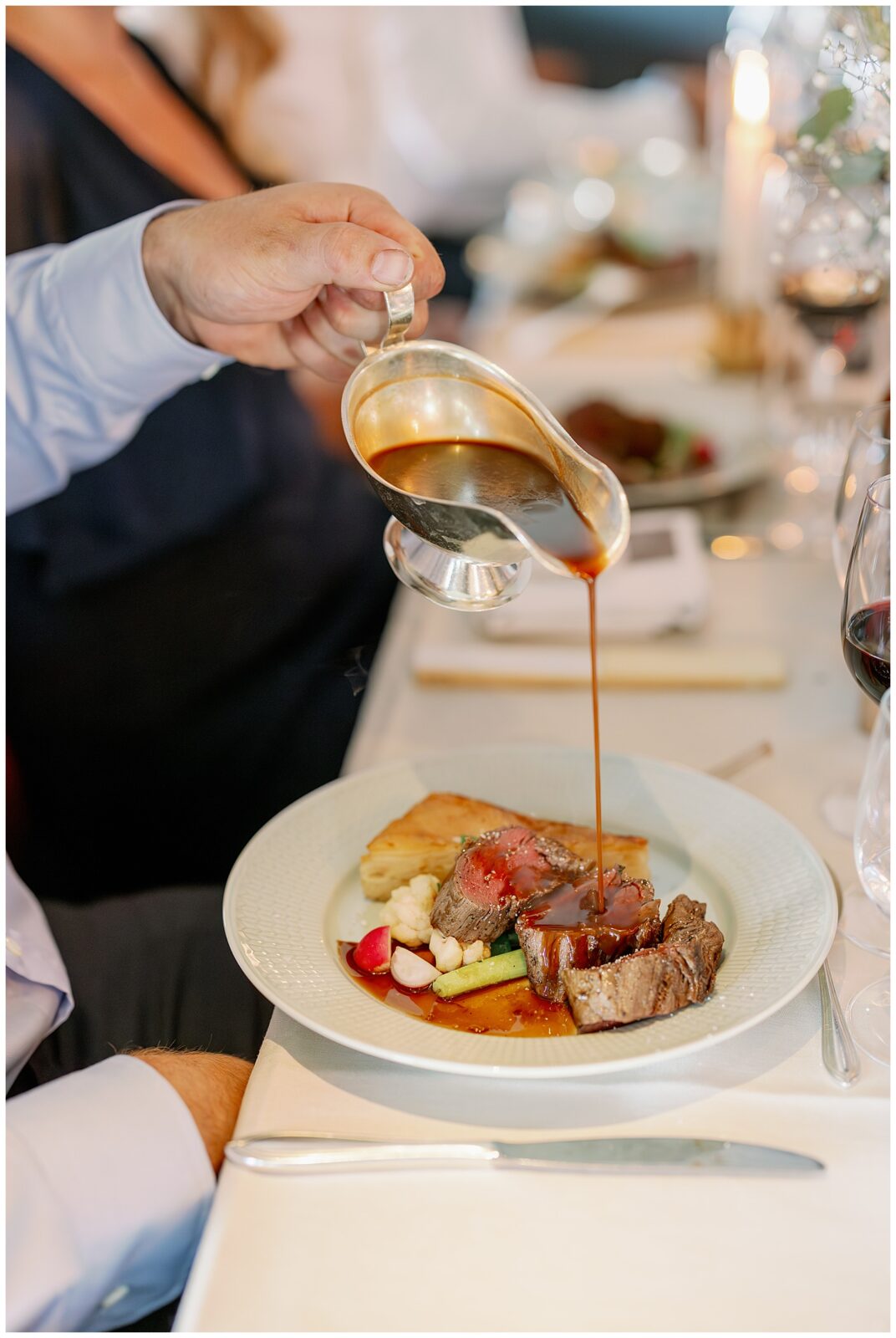 Detaljbild när sås hälls över huvudrätten under bröllopsmiddagen på Green Hotel i Tällberg. A close-up detail of sauce being poured over the main course during the wedding dinner at Green Hotel in Tällberg.